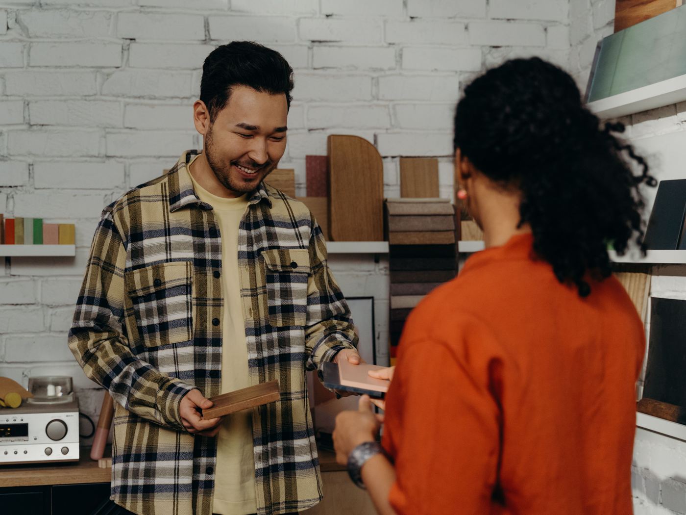 A seller showing a customer a product across the counter of a small audio shop.